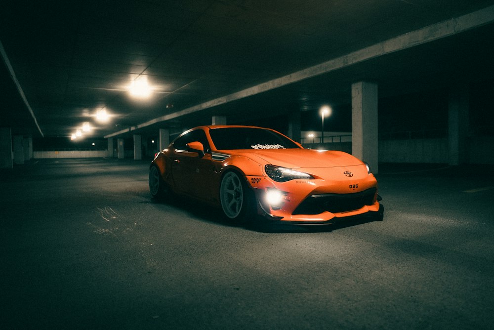 Voiture orange garée dans un parking couvert